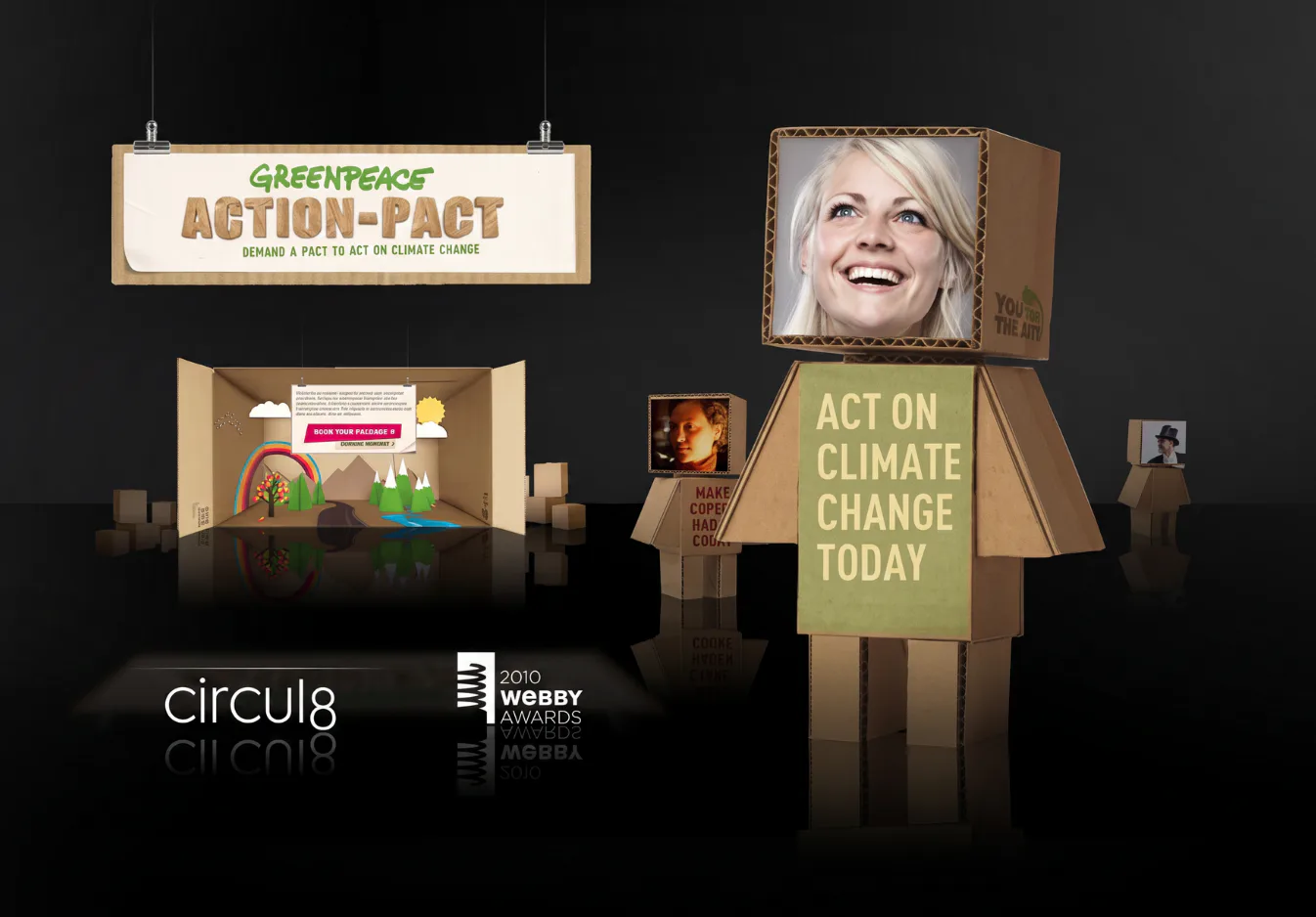 Interactive 3D cardboard box robot characters with user photos displayed on screen, alongside Greenpeace Action Pact campaign banner and 2010 Webby Awards logo against dark background.