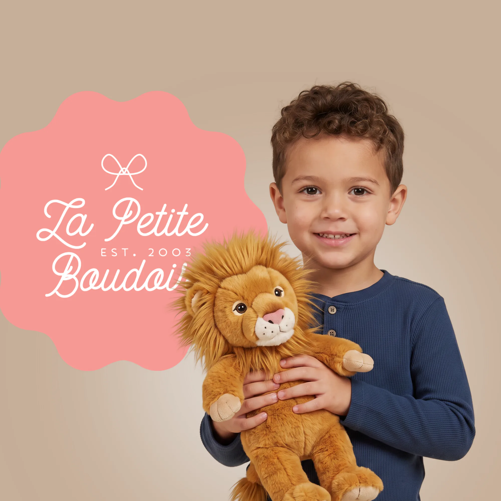 Smiling young boy in navy ribbed sweater holding a golden lion plush toy against beige background with pink La Petite Boudoi logo